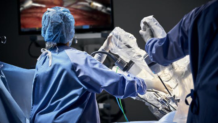 Medical team supervises the Da Vinci robot-assisted procedure on screen.